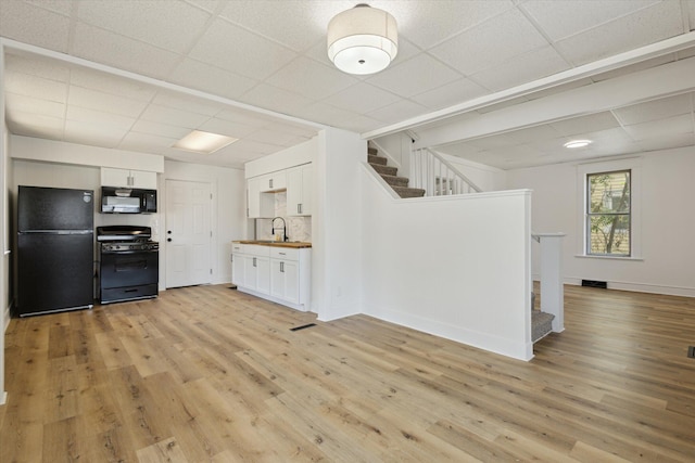 400 Burton St SW, Grand Rapids, MI 49507 - kitchen with black appliances, a paneled ceiling, light wood-type flooring, white cabinets, and open floor plan