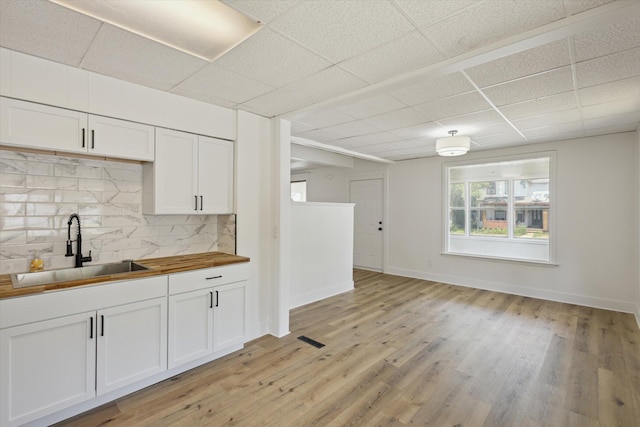 400 Burton St SW, Grand Rapids, MI 49507 - kitchen featuring a drop ceiling, light wood-type flooring, white cabinetry, tasteful backsplash, and wood counters