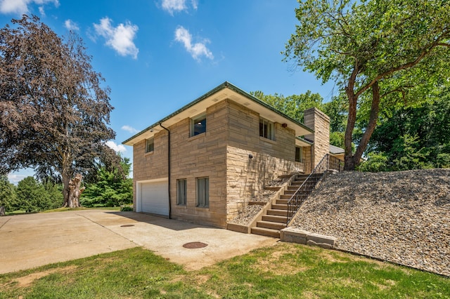 3017 Niles Buchanan Rd, Buchanan, MI 49107 - view of side of home with concrete driveway, stone siding, stairway, an attached garage, and a chimney