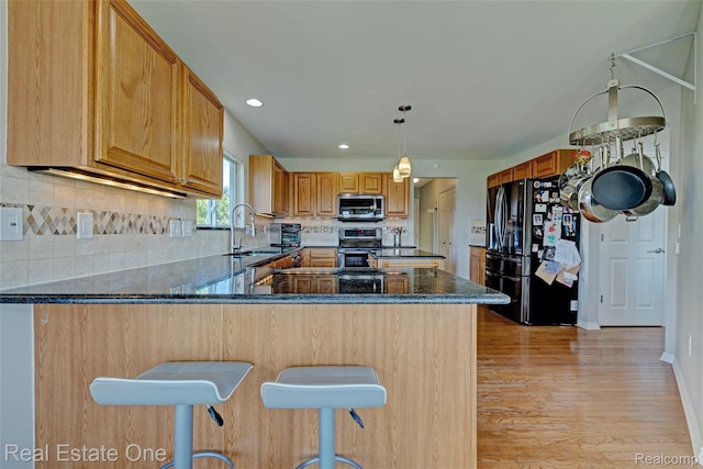 560 Boulder Lake Dr, Oxford, MI 48371 - kitchen featuring stainless steel appliances, light wood-type flooring, a peninsula, dark stone counters, and backsplash