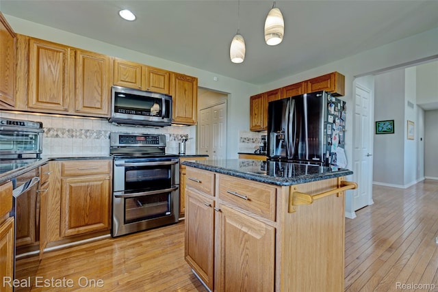 560 Boulder Lake Dr, Oxford, MI 48371 - kitchen with stainless steel appliances, tasteful backsplash, dark stone counters, a kitchen island, and light wood-style flooring