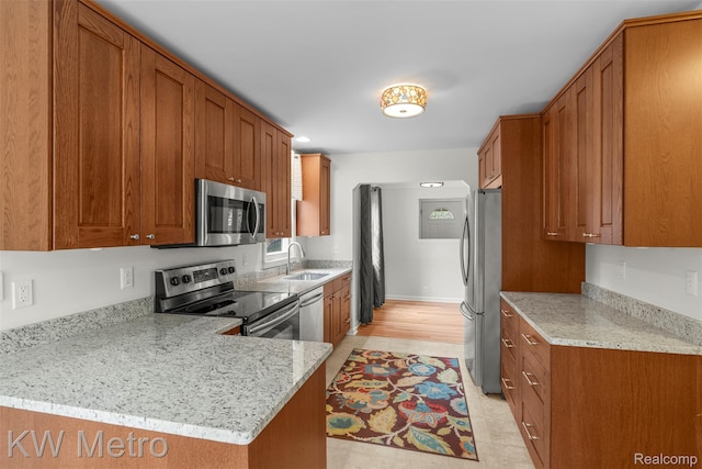 3180 Warringham Ave, Waterford, MI 48329 - kitchen with stainless steel appliances, brown cabinetry, a peninsula, and light stone countertops