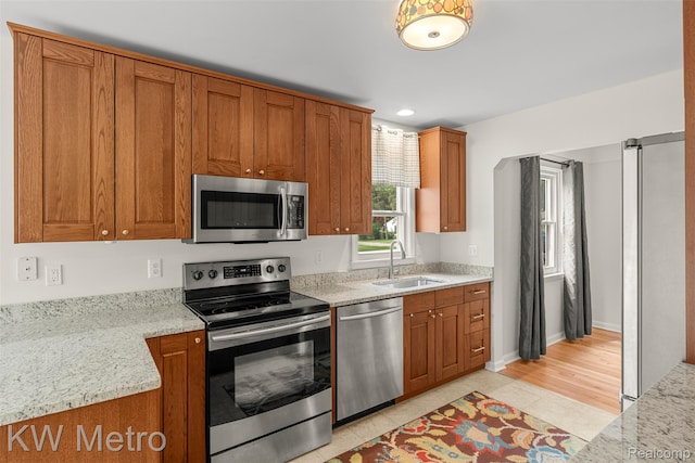 3180 Warringham Ave, Waterford, MI 48329 - kitchen featuring appliances with stainless steel finishes, brown cabinets, light stone countertops, recessed lighting, and light tile patterned floors
