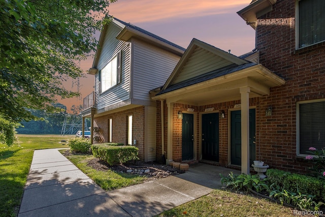 12129 Hidden View Ct, Utica, MI 48315 - exterior entry at dusk featuring brick siding and a lawn