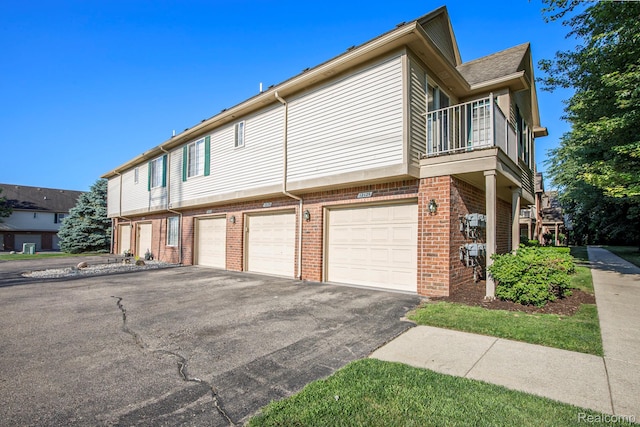 12129 Hidden View Ct, Utica, MI 48315 - view of side of property with a balcony, brick siding, an attached garage, and driveway