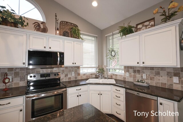 2956 Pebblestone Dr Unit 47, Hudsonville, MI 49426 - kitchen featuring stainless steel appliances, white cabinetry, vaulted ceiling, tasteful backsplash, and dark stone countertops