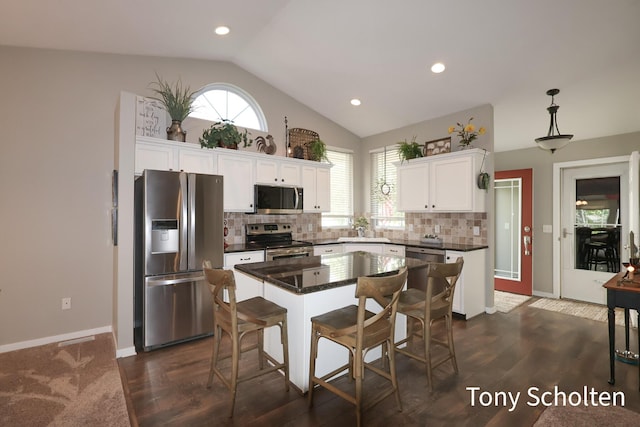 2956 Pebblestone Dr Unit 47, Hudsonville, MI 49426 - kitchen featuring appliances with stainless steel finishes, vaulted ceiling, dark countertops, white cabinetry, and tasteful backsplash
