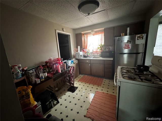 1174 E Holbrook Ave, Flint, MI 48505 - kitchen featuring freestanding refrigerator, white gas stove, light flooring, a drop ceiling, and light countertops