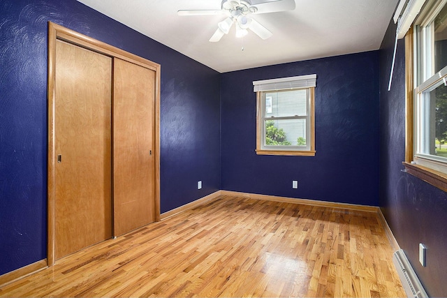 8520 Pennfield Rd, Battle Creek, MI 49017 - unfurnished bedroom with a baseboard radiator, light wood-style flooring, a closet, and ceiling fan