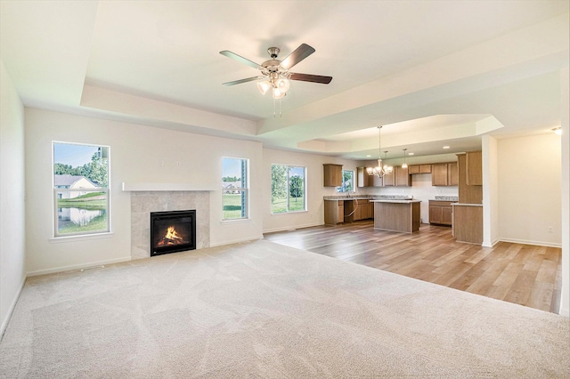 5391 Swan Ln, Burton, MI 48509 - unfurnished living room featuring a raised ceiling, a tile fireplace, a chandelier, light carpet, and a ceiling fan