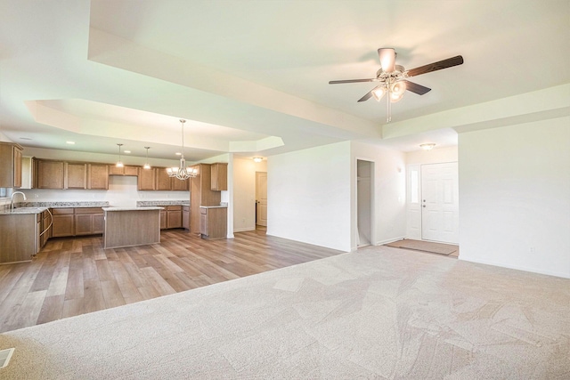 5391 Swan Ln, Burton, MI 48509 - kitchen with a tray ceiling, open floor plan, a center island, a ceiling fan, and a chandelier