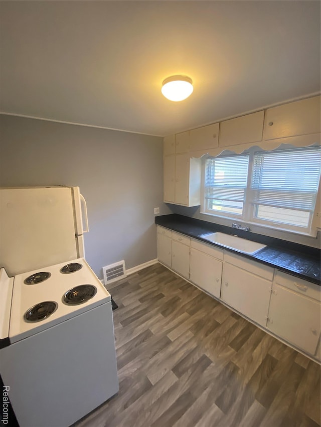 1112 Minnie St, Port Huron, MI 48060 - kitchen with white appliances, dark countertops, dark wood-style floors, and white cabinets