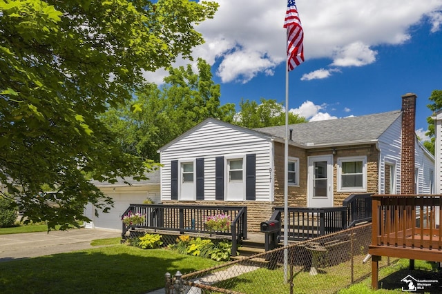 917 E 8th St, Monroe, MI 48161 - view of front facade featuring stone siding, a wooden deck, an attached garage, driveway, and a shingled roof