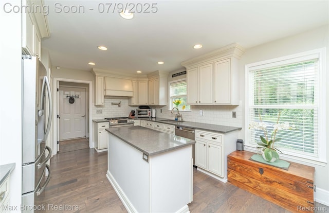 1478 Courtney Ct, Hartland, MI 48353 - kitchen featuring appliances with stainless steel finishes, dark wood-type flooring, a kitchen island, decorative backsplash, and stone countertops