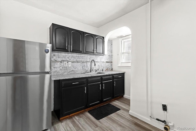 4200 Lois St, Dearborn, MI 48126 - kitchen with freestanding refrigerator, light wood finished floors, dark cabinetry, light stone countertops, and tasteful backsplash