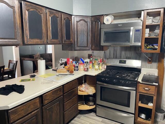 166 N Clay St, Coldwater, MI 49036 - kitchen with stainless steel appliances, light countertops, dark brown cabinets, light wood-type flooring, and decorative backsplash