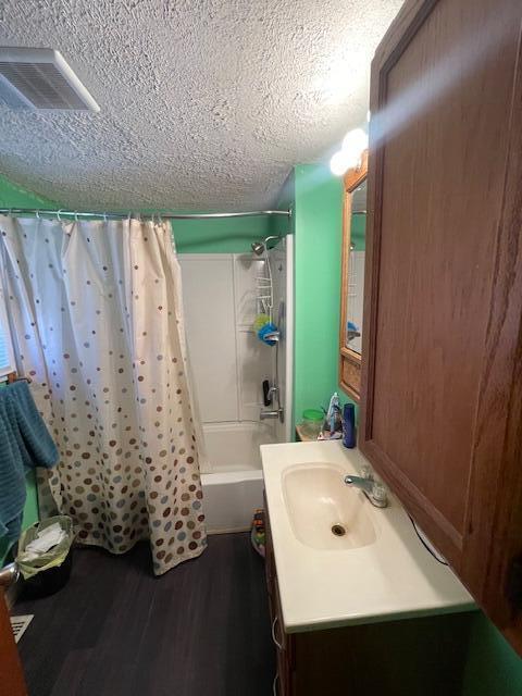 166 N Clay St, Coldwater, MI 49036 - full bathroom with a textured ceiling, vanity, shower / bathtub combination with curtain, and wood finished floors