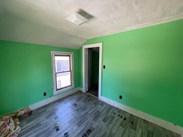 166 N Clay St, Coldwater, MI 49036 - unfurnished bedroom featuring a textured ceiling, vaulted ceiling, and dark wood finished floors