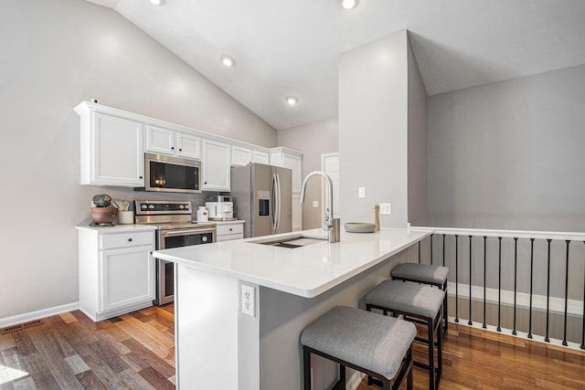 3457 Easy St, Saint Joseph, MI 49085 - kitchen with appliances with stainless steel finishes, a kitchen breakfast bar, dark wood-style flooring, white cabinets, and lofted ceiling