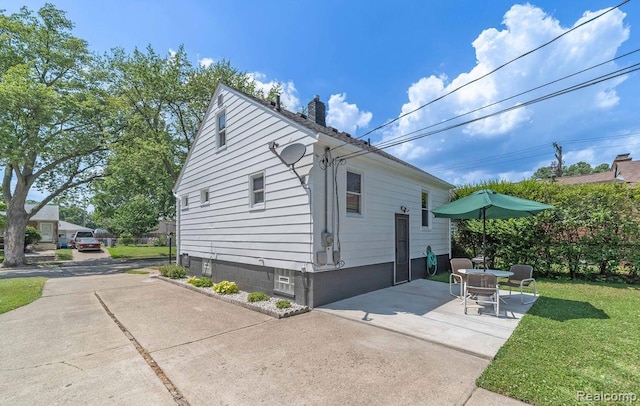 20892 Dean St, Warren, MI 48091 - view of side of home with a chimney, a yard, and a patio area