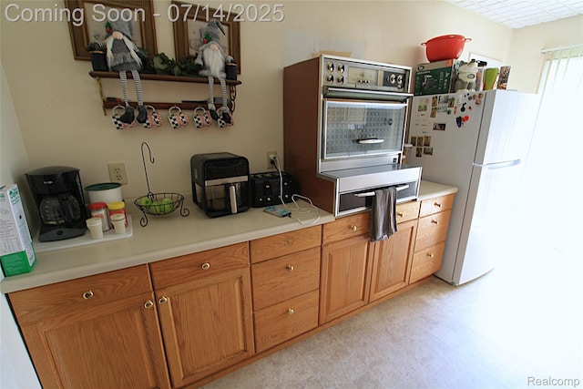 116 N Shiawassee St, Bancroft, MI 48414 - kitchen with freestanding refrigerator, light countertops, and brown cabinetry