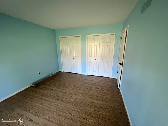 13939 Harrington Dr, Warren, MI 48088 - unfurnished bedroom with multiple closets and dark wood-style floors