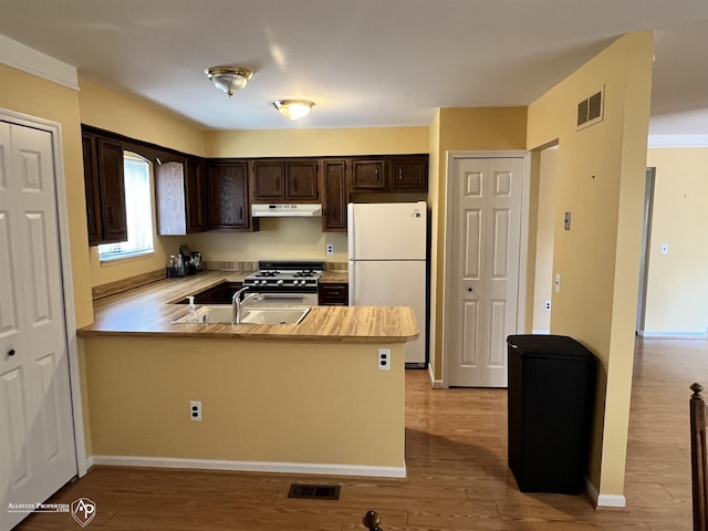 13939 Harrington Dr, Warren, MI 48088 - kitchen featuring freestanding refrigerator, dark brown cabinetry, gas stove, a peninsula, and wood finished floors