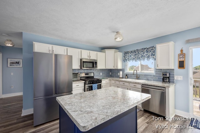 1698 Trent Ridge Ct NE, Cedar Springs, MI 49319 - kitchen featuring appliances with stainless steel finishes, decorative backsplash, white cabinets, a center island, and a textured ceiling
