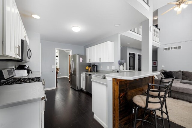 507 Illinois Dr, Tecumseh, MI 49286 - kitchen featuring appliances with stainless steel finishes, a kitchen bar, white cabinets, a peninsula, and dark wood-style floors