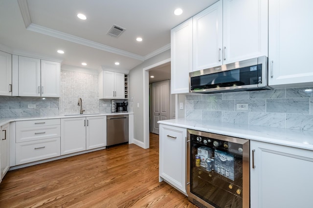 5680 Woodland Ave, Watervliet, MI 49098 - kitchen featuring wine cooler, appliances with stainless steel finishes, crown molding, decorative backsplash, and white cabinets