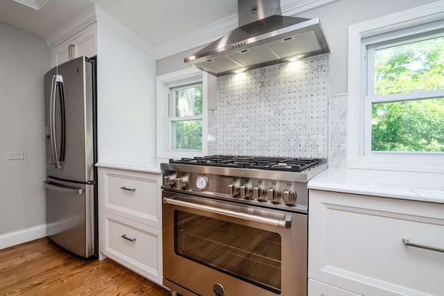 5680 Woodland Ave, Watervliet, MI 49098 - kitchen with stainless steel appliances, wall chimney exhaust hood, tasteful backsplash, white cabinets, and light wood finished floors