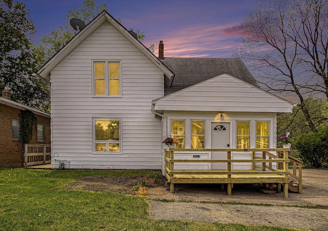 22121 Bedford Rd N, Battle Creek, MI 49017 - back of house at dusk featuring a deck and a yard