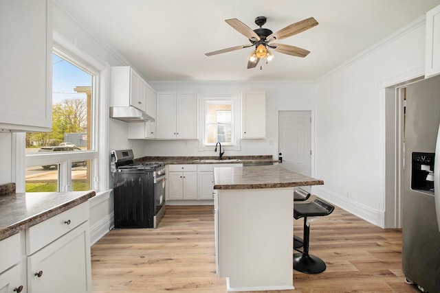 22121 Bedford Rd N, Battle Creek, MI 49017 - kitchen with appliances with stainless steel finishes, under cabinet range hood, a breakfast bar, light wood-style floors, and crown molding