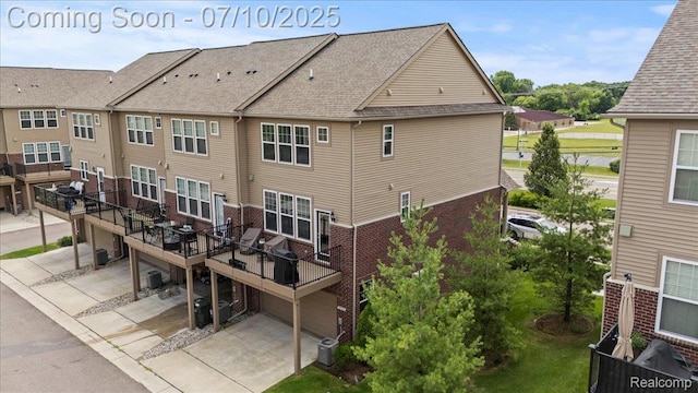 2582 Helmsdale Cir, Rochester, MI 48307 - rear view of property featuring an attached garage, brick siding, a wooden deck, a patio area, and driveway