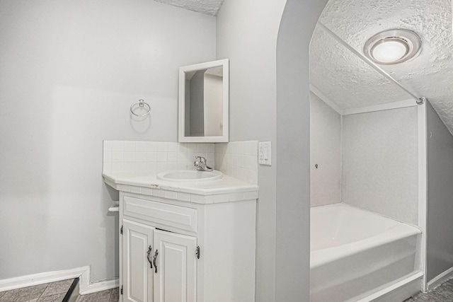 5643 Ivanrest Ave SW, Wyoming, MI 49418 - bathroom featuring a textured ceiling, vanity, a tub, and backsplash