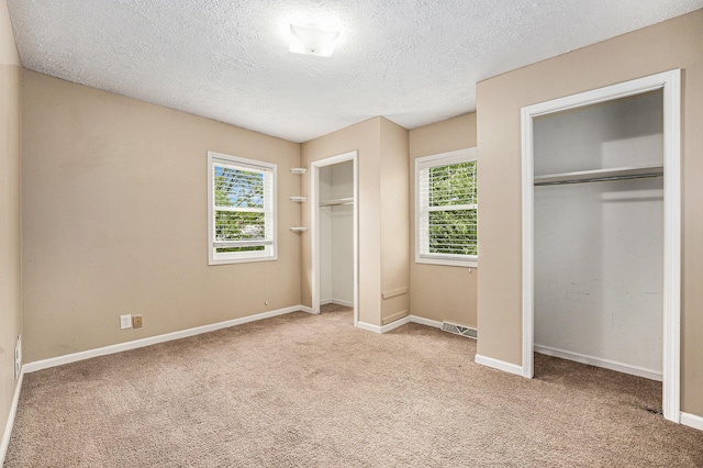5643 Ivanrest Ave SW, Wyoming, MI 49418 - unfurnished bedroom featuring multiple closets, a textured ceiling, and carpet flooring