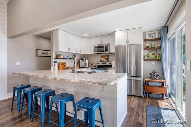 11986 Reyburn Dr NE, Sparta, MI 49345 - kitchen with stainless steel appliances, dark wood-style flooring, light countertops, white cabinets, and a peninsula
