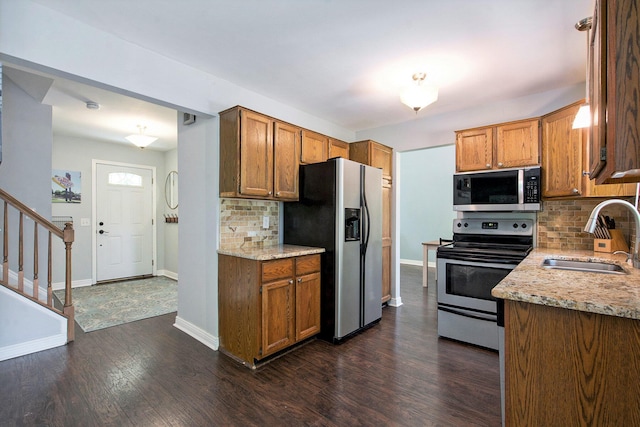7981 Faircrest Dr, Ypsilanti, MI 48197 - kitchen featuring appliances with stainless steel finishes, decorative backsplash, dark wood finished floors, and brown cabinetry