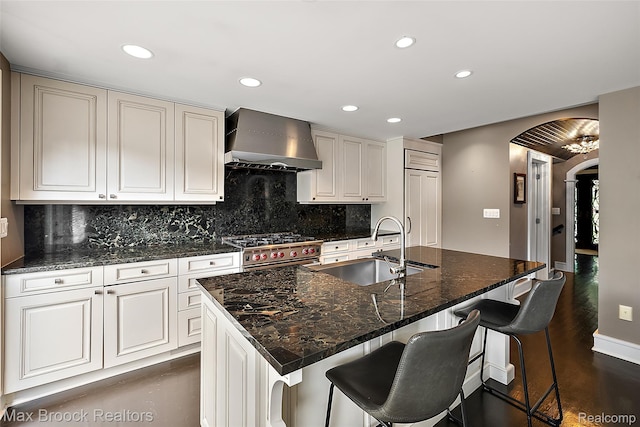 504 Landon St, Birmingham, MI 48009 - kitchen featuring wall chimney exhaust hood, stainless steel range, arched walkways, recessed lighting, and backsplash