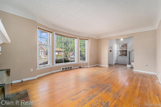 74 Chestnut St, River Rouge, MI 48218 - unfurnished living room with a textured ceiling, hardwood / wood-style flooring, and stairs