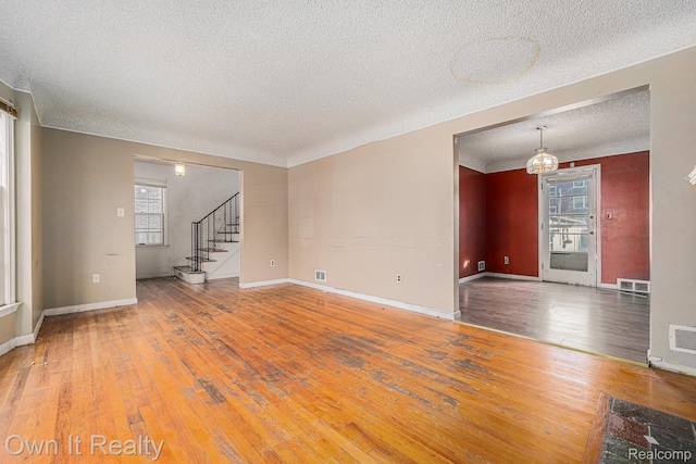 74 Chestnut St, River Rouge, MI 48218 - unfurnished living room featuring a textured ceiling, wood-type flooring, stairway, and a chandelier