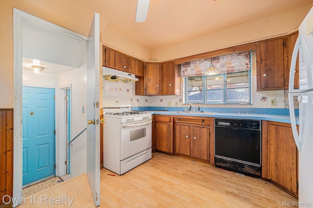 74 Chestnut St, River Rouge, MI 48218 - kitchen with white appliances, under cabinet range hood, brown cabinets, and decorative backsplash