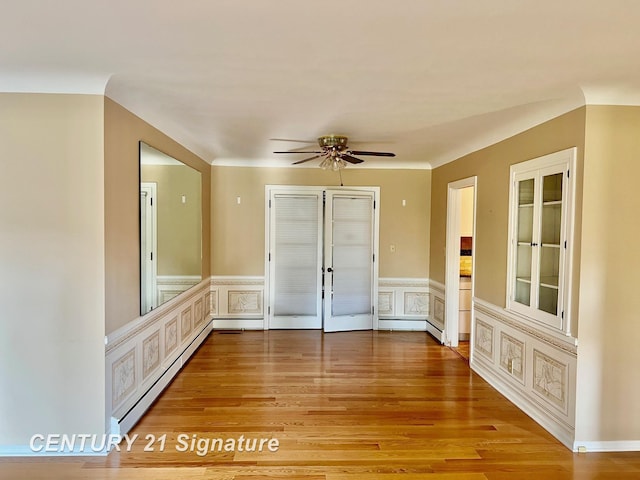 1751 Lathrup Ave, Saginaw, MI 48638 - spare room with a baseboard heating unit, light wood finished floors, a decorative wall, a ceiling fan, and a wainscoted wall