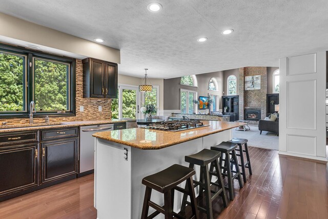 3800 Guest Rd, Jackson, MI 49203 - kitchen with appliances with stainless steel finishes, a textured ceiling, a breakfast bar area, hardwood / wood-style flooring, and recessed lighting