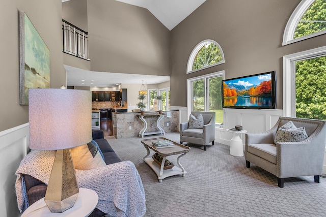 3800 Guest Rd, Jackson, MI 49203 - carpeted living area featuring healthy amount of natural light, high vaulted ceiling, and wainscoting