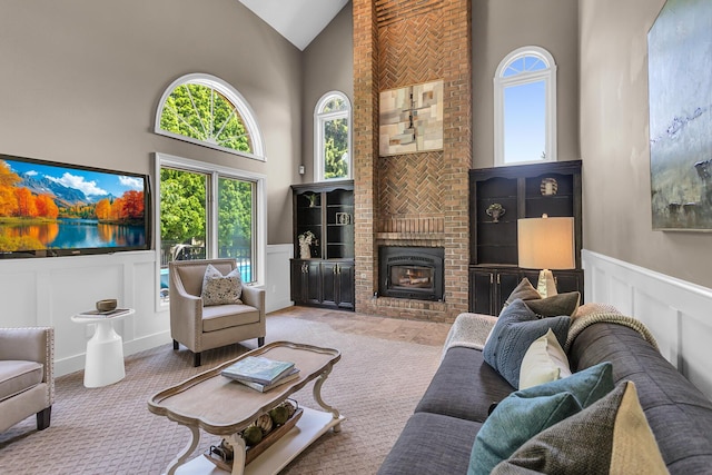 3800 Guest Rd, Jackson, MI 49203 - carpeted living room with high vaulted ceiling, a decorative wall, wainscoting, and a brick fireplace