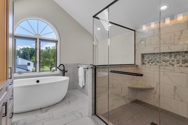 3800 Guest Rd, Jackson, MI 49203 - bathroom with marble look tiles, a freestanding tub, a shower stall, tile walls, and lofted ceiling