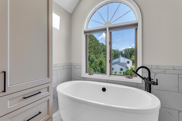 3800 Guest Rd, Jackson, MI 49203 - full bathroom featuring tile walls, a soaking tub, marble finish floors, and wainscoting