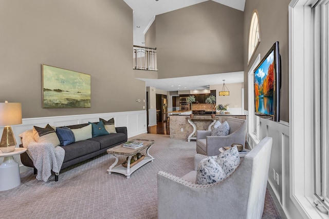 3800 Guest Rd, Jackson, MI 49203 - carpeted living room featuring a towering ceiling, wainscoting, and a decorative wall