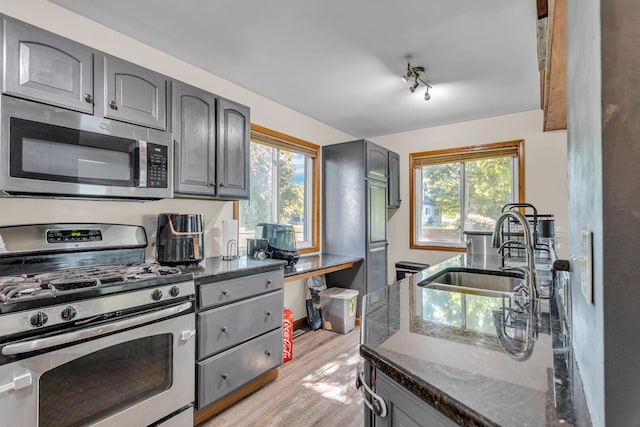 226 Briscoe Pl, Jackson, MI 49203 - kitchen featuring appliances with stainless steel finishes, gray cabinetry, light wood-style floors, and dark stone counters